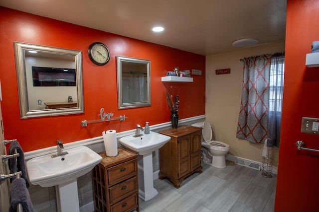 bathroom with dual sinks and toilet