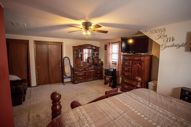 bedroom featuring two closets, light carpet, and ceiling fan