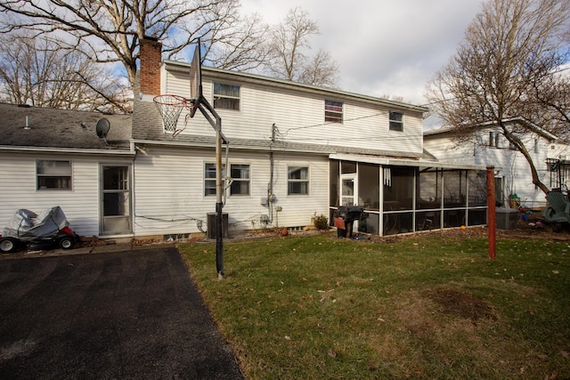 rear view of house with a yard, a sunroom, and central air condition unit