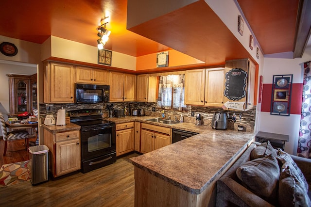 kitchen featuring sink, hardwood / wood-style floors, black appliances, decorative backsplash, and kitchen peninsula