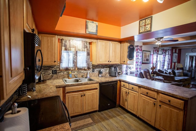 kitchen featuring sink, wood-type flooring, black appliances, decorative backsplash, and kitchen peninsula