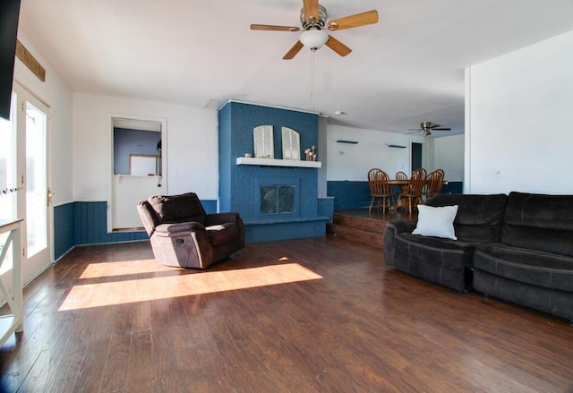 living room with dark hardwood / wood-style floors, a large fireplace, and ceiling fan