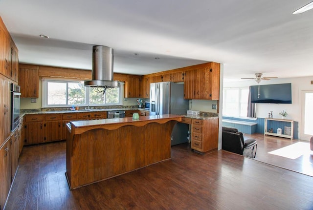 kitchen with dark wood-type flooring, island range hood, kitchen peninsula, ceiling fan, and stainless steel appliances