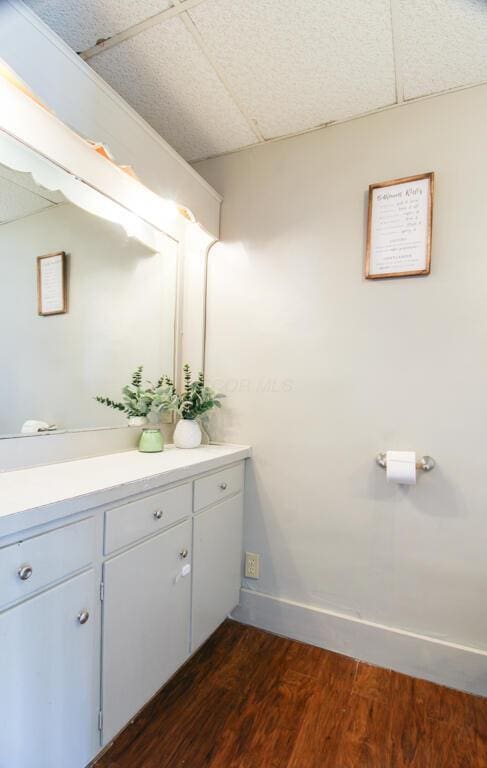 bathroom featuring vanity, hardwood / wood-style floors, and a drop ceiling