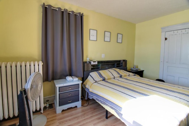 bedroom featuring radiator heating unit and light hardwood / wood-style flooring