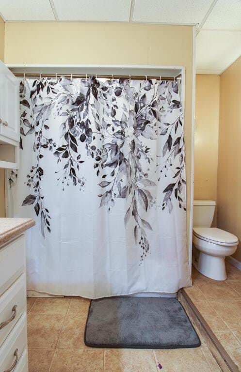 bathroom with vanity, tile patterned flooring, a paneled ceiling, and toilet