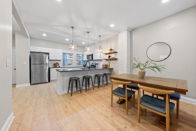 interior space featuring pendant lighting, white cabinetry, stainless steel appliances, a kitchen bar, and kitchen peninsula