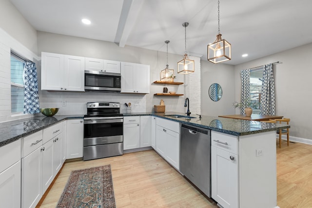 kitchen featuring white cabinetry, hanging light fixtures, kitchen peninsula, and appliances with stainless steel finishes