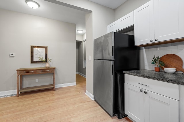 kitchen featuring white cabinetry, decorative backsplash, light hardwood / wood-style flooring, and stainless steel refrigerator