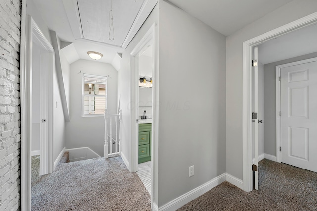 hallway with carpet, sink, and lofted ceiling