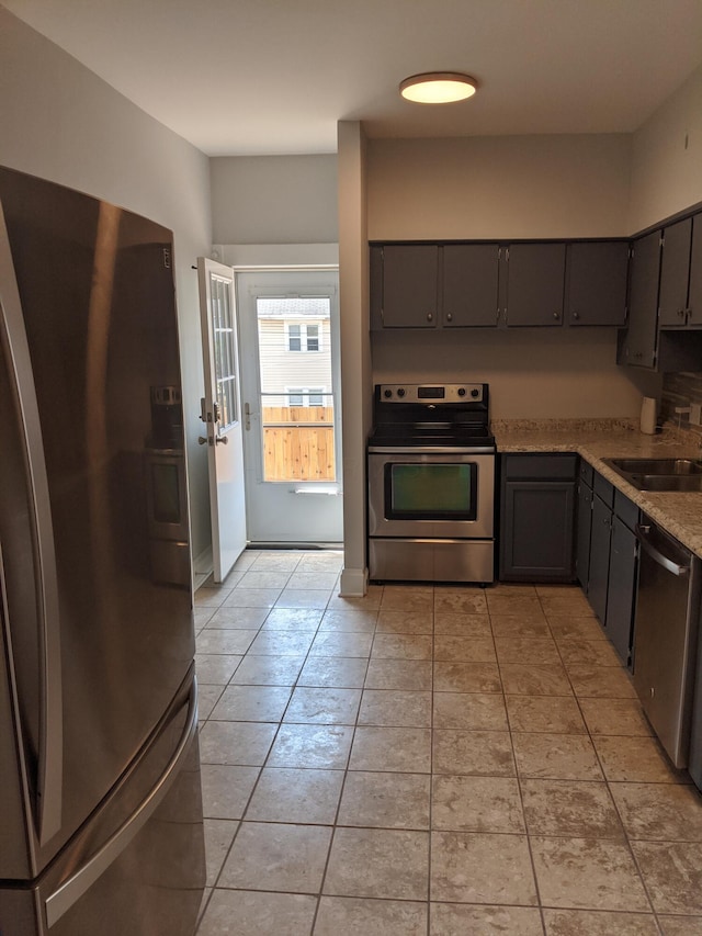 kitchen featuring stainless steel appliances, light stone countertops, sink, and light tile patterned floors