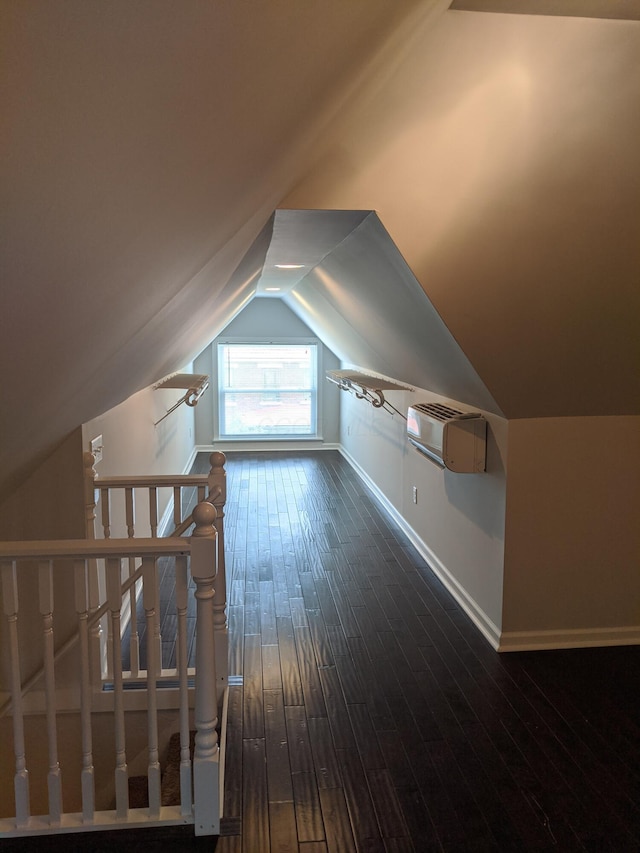 additional living space featuring dark hardwood / wood-style flooring, lofted ceiling, and an AC wall unit