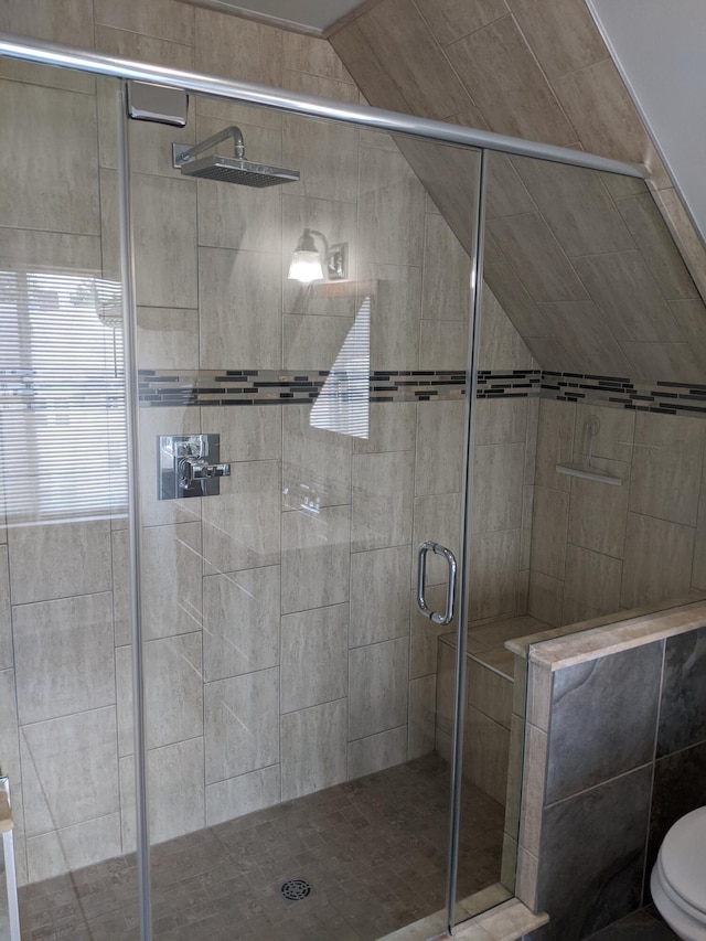 bathroom with vaulted ceiling, toilet, and a shower with door