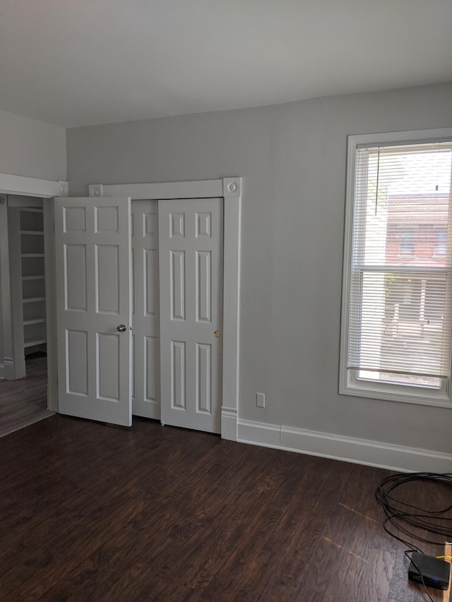 unfurnished bedroom with dark hardwood / wood-style flooring and a closet