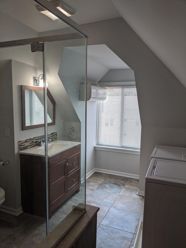 bathroom with independent washer and dryer, vanity, decorative backsplash, vaulted ceiling, and toilet