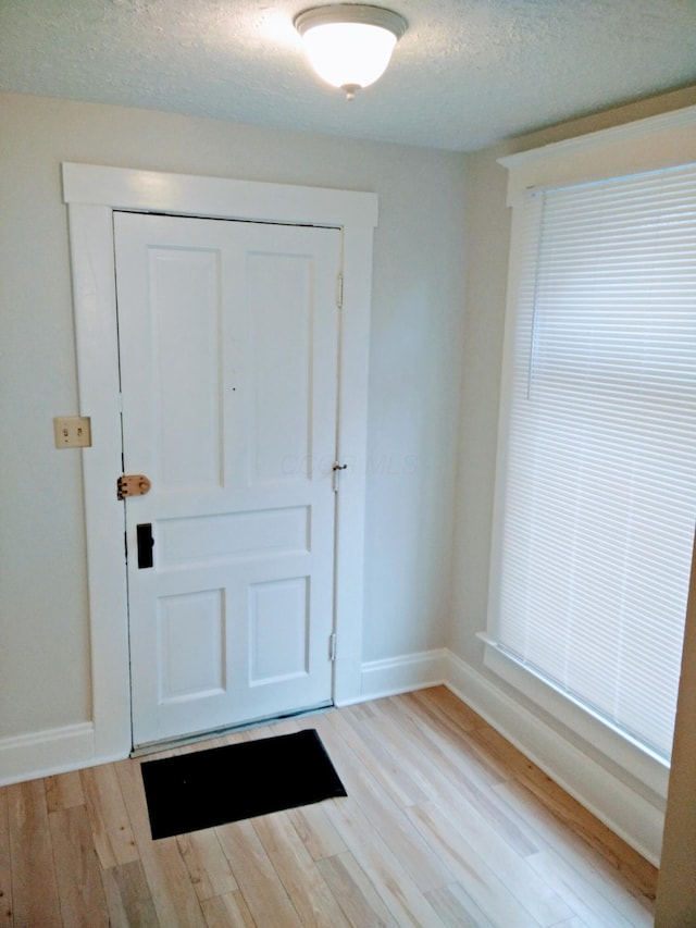 entryway with a textured ceiling and light hardwood / wood-style floors