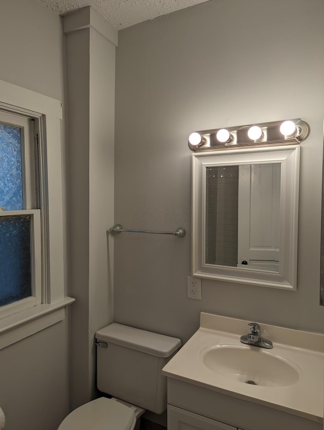 bathroom with vanity, toilet, and a textured ceiling