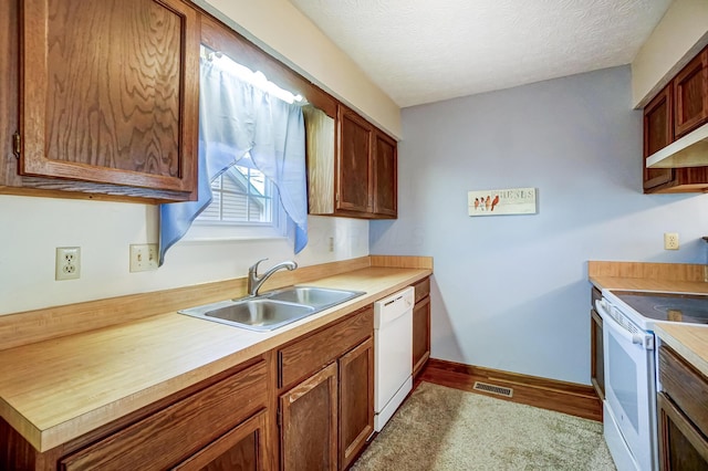 kitchen with light carpet, sink, white appliances, and a textured ceiling