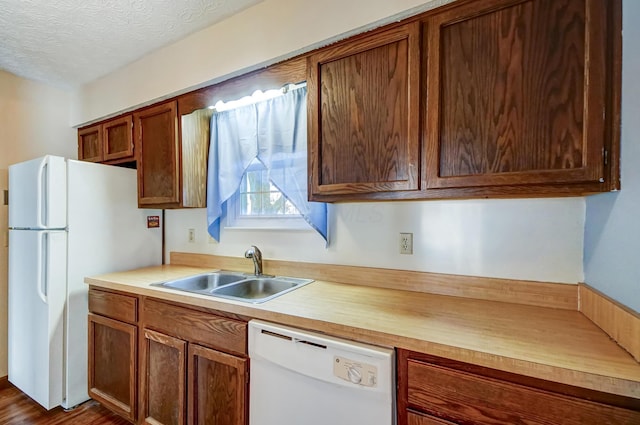 kitchen with dark wood-type flooring, white appliances, sink, and a textured ceiling