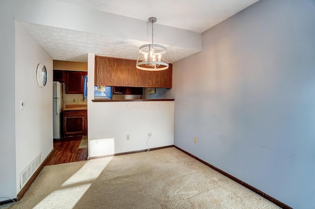 carpeted spare room with a notable chandelier and a textured ceiling