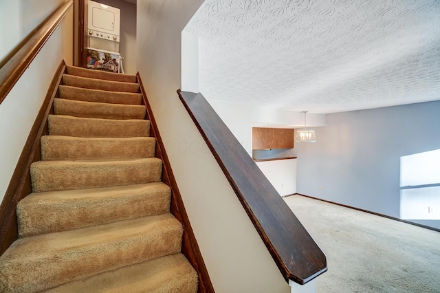 staircase with a notable chandelier, a textured ceiling, and carpet flooring