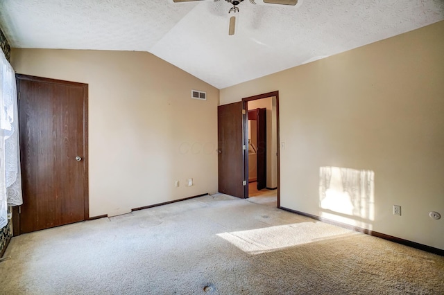 carpeted spare room with ceiling fan, lofted ceiling, and a textured ceiling