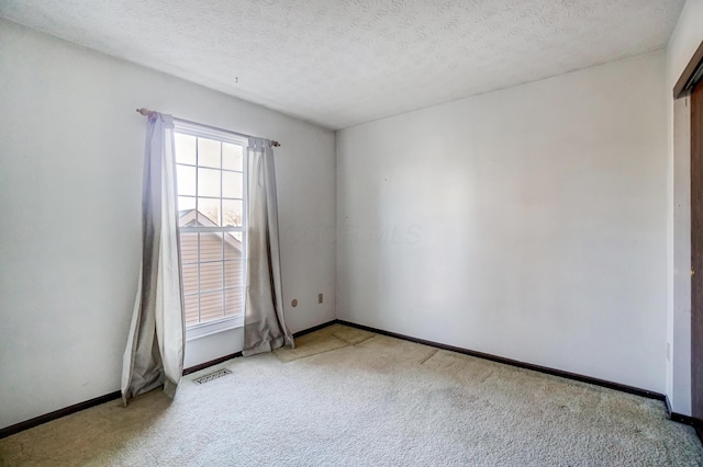 carpeted spare room featuring a textured ceiling