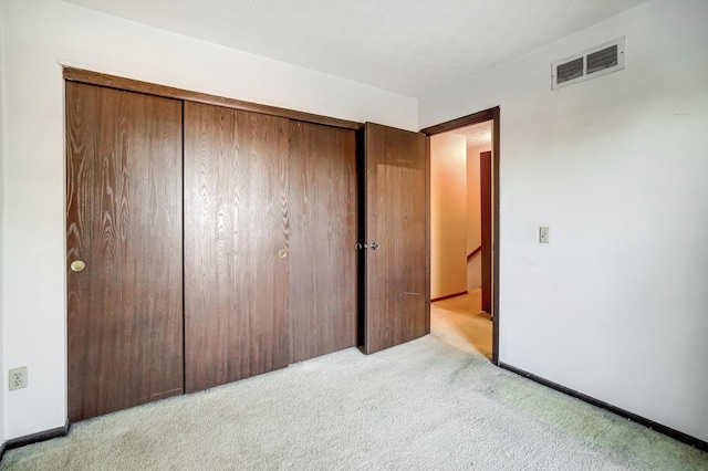 unfurnished bedroom with light carpet and a closet