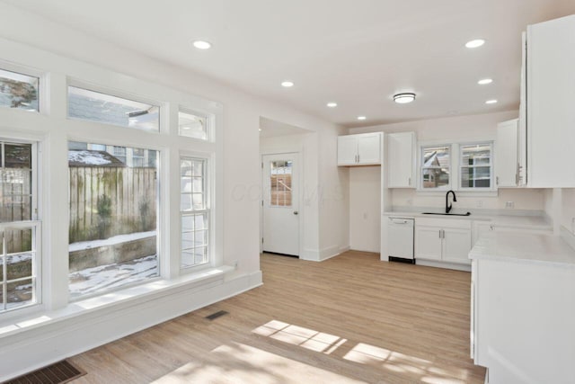 kitchen with dishwasher, sink, white cabinets, and light hardwood / wood-style flooring