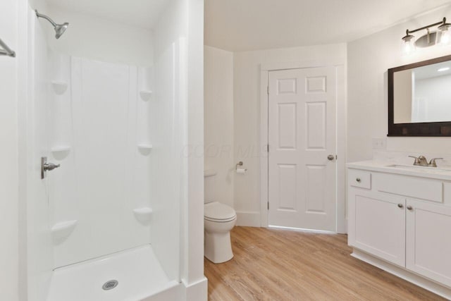 bathroom with wood-type flooring, a shower, vanity, and toilet