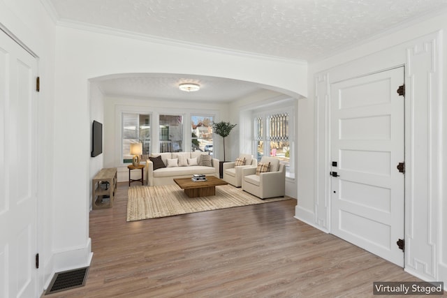 living room featuring wood-type flooring, ornamental molding, and a textured ceiling