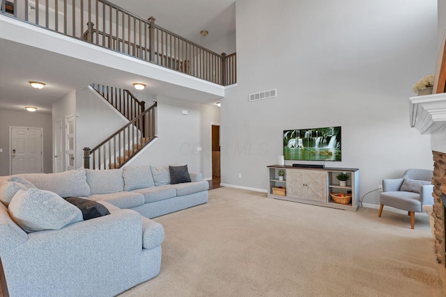 living room featuring a towering ceiling, a fireplace, and carpet