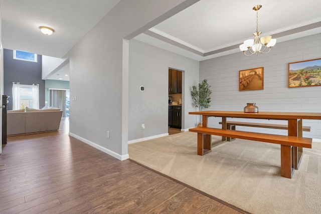 dining space featuring ornamental molding, a raised ceiling, hardwood / wood-style floors, and a notable chandelier