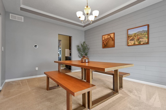 carpeted dining space featuring a raised ceiling, crown molding, an inviting chandelier, and wood walls