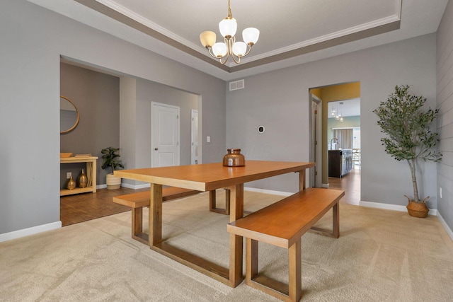 carpeted dining area with crown molding, a notable chandelier, and a tray ceiling