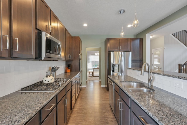 kitchen featuring pendant lighting, sink, appliances with stainless steel finishes, dark stone countertops, and decorative backsplash