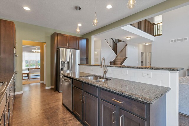 kitchen featuring pendant lighting, sink, stainless steel appliances, a center island with sink, and dark hardwood / wood-style flooring