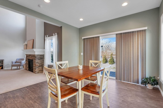 dining area featuring plenty of natural light, dark hardwood / wood-style floors, and a stone fireplace