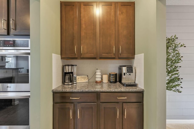 kitchen featuring decorative backsplash, dark stone counters, and stainless steel double oven