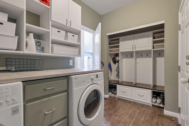 washroom with dark wood-type flooring, cabinets, washer / dryer, and a textured ceiling