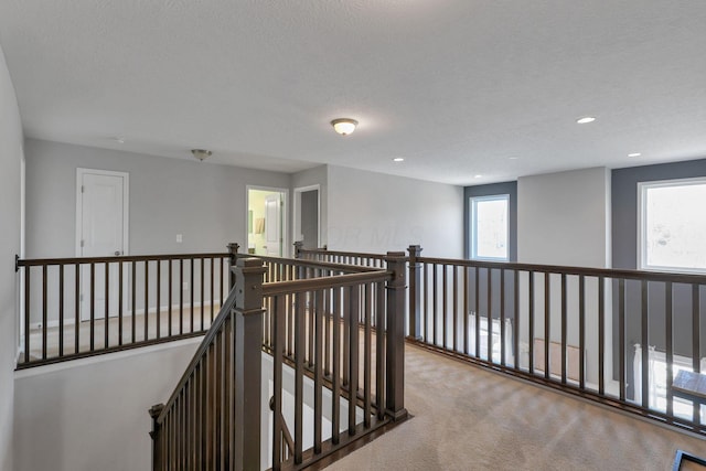 corridor featuring light colored carpet and a textured ceiling