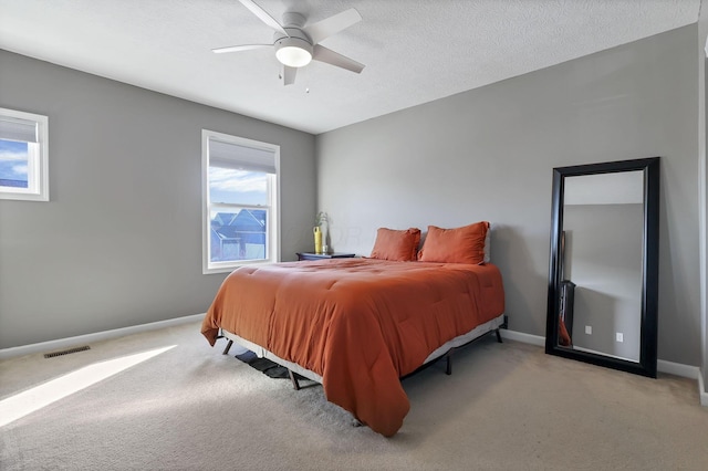 carpeted bedroom with multiple windows, a textured ceiling, and ceiling fan