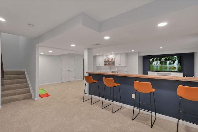 bar featuring white cabinetry, decorative backsplash, and light carpet