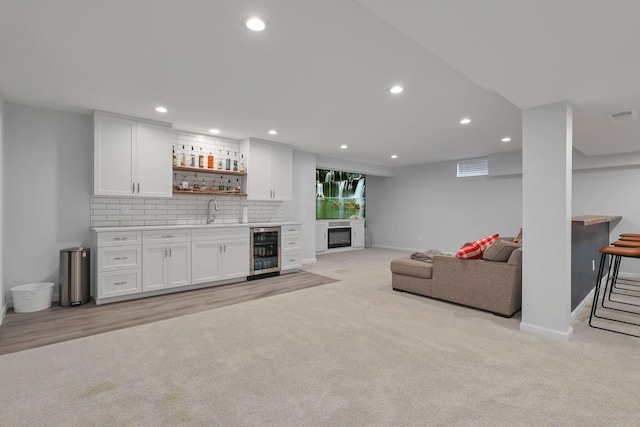 living room with beverage cooler, light carpet, and indoor wet bar