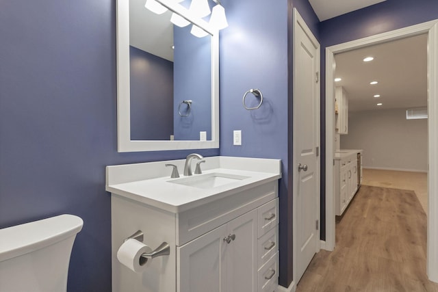 bathroom with hardwood / wood-style flooring, vanity, and toilet