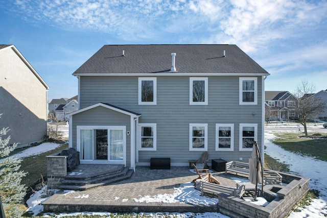 snow covered rear of property featuring a wooden deck, a patio area, and an outdoor fire pit