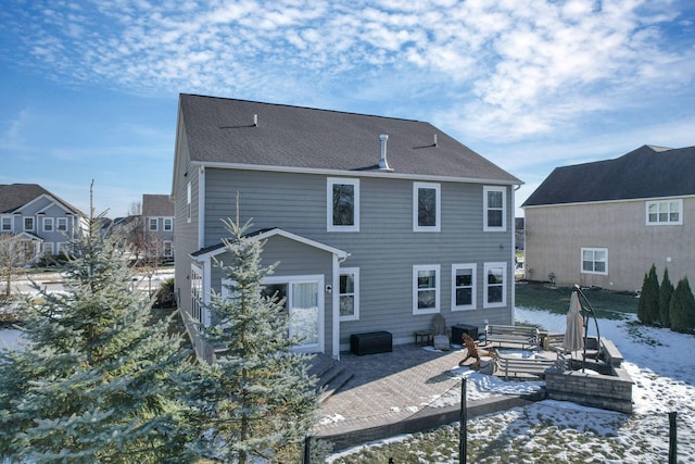 snow covered back of property with a patio