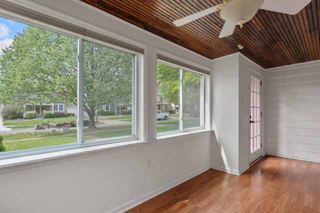 unfurnished sunroom with wood ceiling, wood walls, wood finished floors, and baseboards