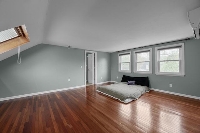 bedroom featuring baseboards, wood-type flooring, a wall mounted AC, and vaulted ceiling