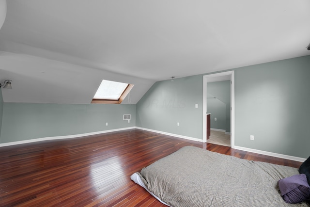 bedroom with lofted ceiling with skylight, baseboards, visible vents, and wood finished floors